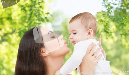 Image of mother kissing baby over green natural background