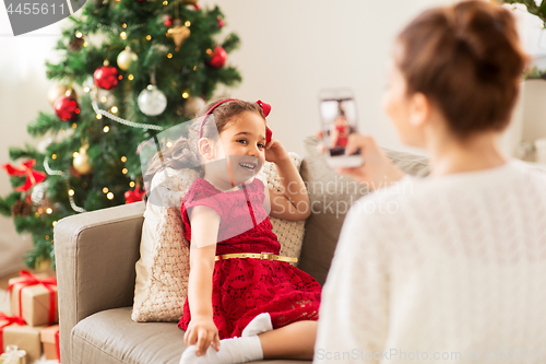 Image of mother picturing daughter by phone on christmas