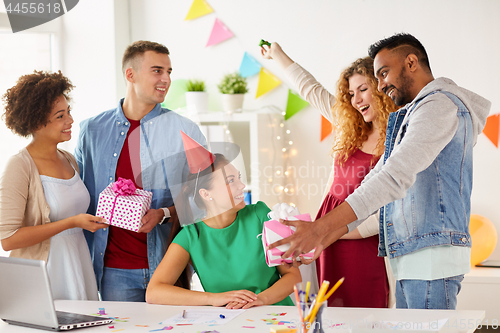 Image of team greeting colleague at office birthday party