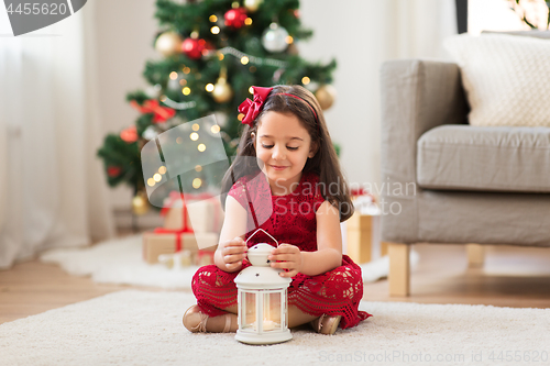 Image of little girl with lantern at home on christmas