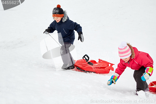 Image of kids with sleds climbing snow hill in winter