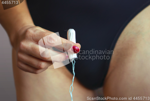 Image of hand of woman with white tampon 