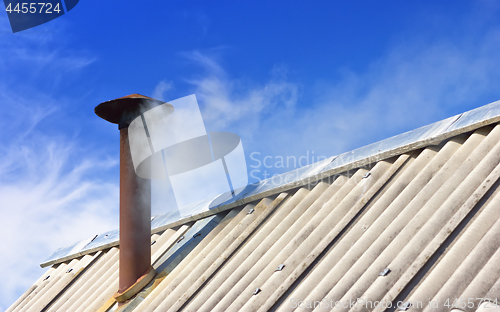 Image of Smoke From The Chimney On The Old Roof Against The Blue Sky 