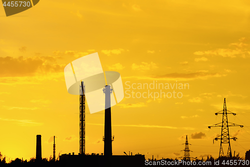 Image of Industrial landscape with silhouettes of pipes and towers agains