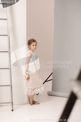 Image of Little pretty girl with flowers dressed in wedding dresses