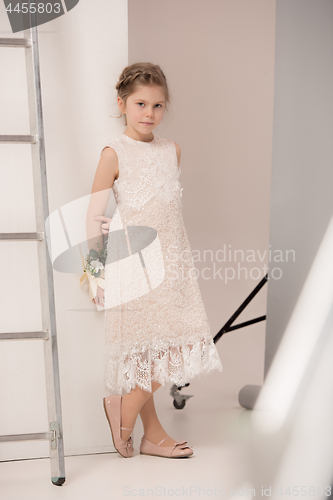 Image of Little pretty girl with flowers dressed in wedding dresses