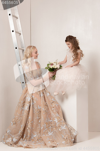 Image of Little pretty girls with flowers dressed in wedding dresses