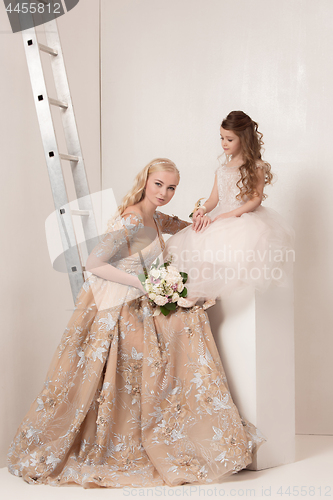 Image of Little pretty girls with flowers dressed in wedding dresses