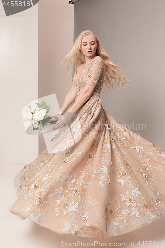 Image of Bride in beautiful dress standing indoors in white studio interior like at home. Trendy wedding style shot. Young attractive caucasian model like a bride tender looking.