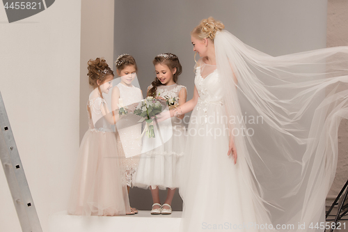 Image of Little pretty girls with flowers dressed in wedding dresses