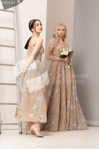 Image of Brides in beautiful dress standing indoors in white studio interior like at home. Trendy wedding style shot. Young attractive caucasian model like a bride tender looking.