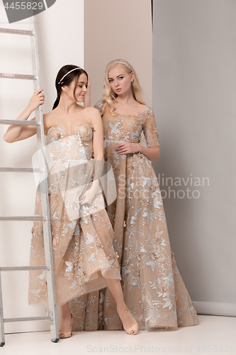 Image of Brides in beautiful dress standing indoors in white studio interior like at home. Trendy wedding style shot. Young attractive caucasian model like a bride tender looking.
