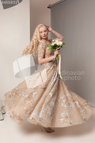 Image of Bride in beautiful dress standing indoors in white studio interior like at home. Trendy wedding style shot. Young attractive caucasian model like a bride tender looking.