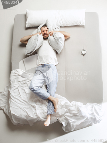 Image of Top view photo of young man sleeping in a big white bed