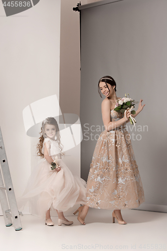 Image of Little pretty girls with flowers dressed in wedding dresses