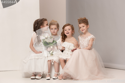 Image of Little pretty girls with flowers dressed in wedding dresses