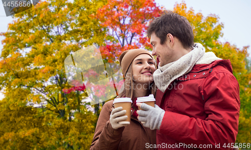 Image of happy couple with coffee walking in autumn park