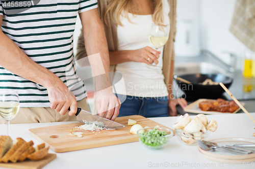 Image of couple cooking food and drinking wine at home