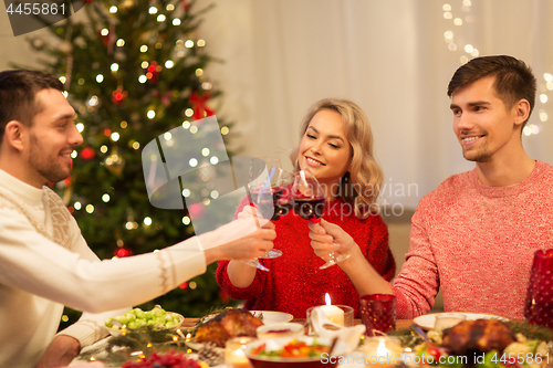 Image of happy friends drinking red wine at christmas party