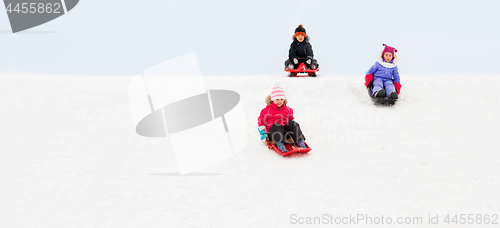 Image of kids sliding on sleds down snow hill in winter