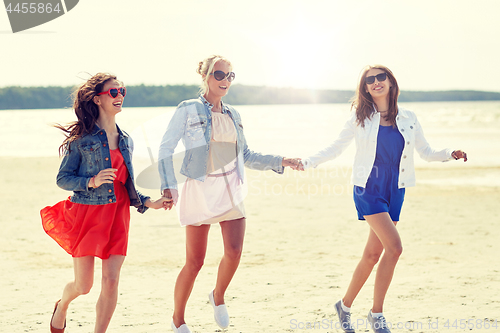 Image of group of smiling women in sunglasses on beach