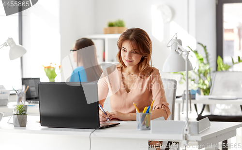 Image of businesswoman with laptop working at office