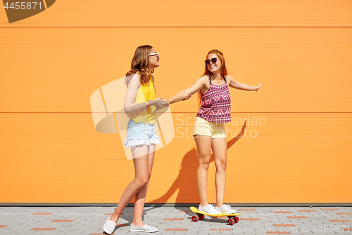 Image of teenage girls riding skateboard on city street