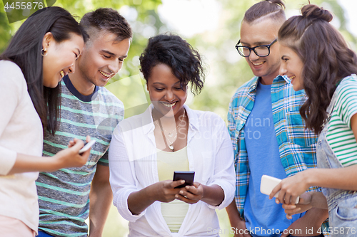 Image of group of happy friends with smartphone outdoors