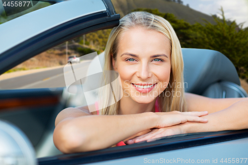 Image of happy woman in convertible car over big sur hills 