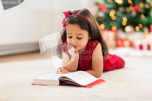 Image of happy girl reading book at home on christmas