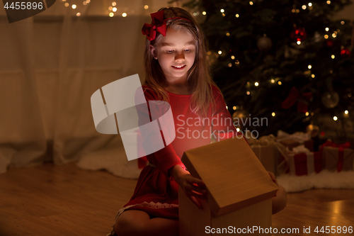 Image of smiling girl opening christmas gift at night