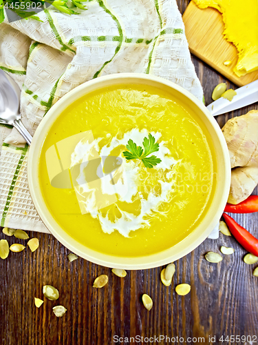 Image of Soup-puree pumpkin with cream and parsley in bowl on board top