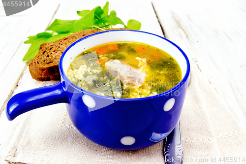 Image of Soup with couscous and spinach in blue bowl on napkin