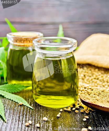 Image of Oil hemp in two jars and flour in spoon on wooden board