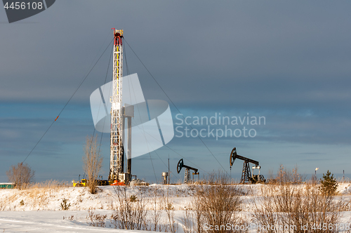 Image of Oil field. Drilling rig and oil pump.