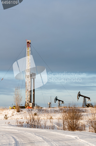 Image of Oil field. Drilling rig and oil pump.