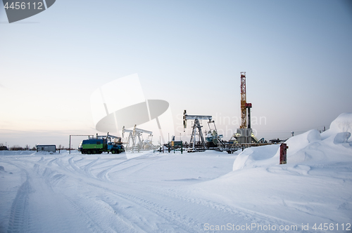 Image of Oil field. Drilling rig and oil pump.