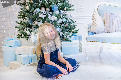 Image of Cute girl sitting near Christmas Tree