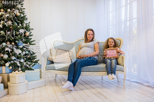 Image of Beautiful pregnant woman sitting with doughter