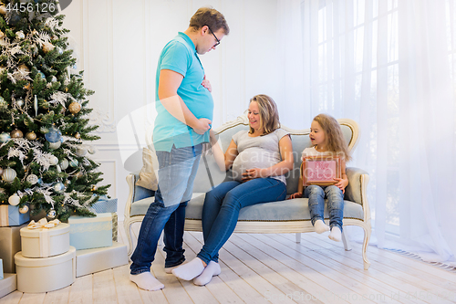 Image of Beautiful pregnant woman sitting with doughter and husband