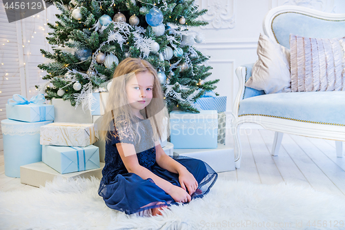 Image of Cute girl sitting near Christmas Tree