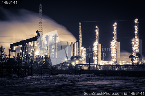 Image of Pump jack and refinery at night.