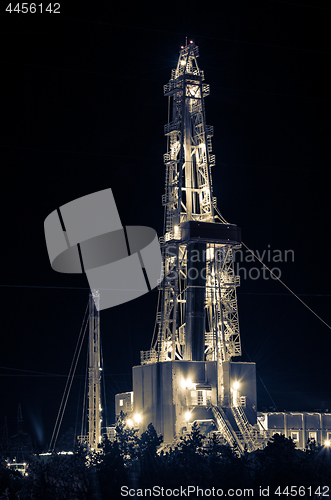 Image of Oil field. Drilling rig at night.