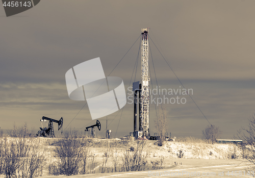 Image of Oil field. Drilling rig and oil pump.