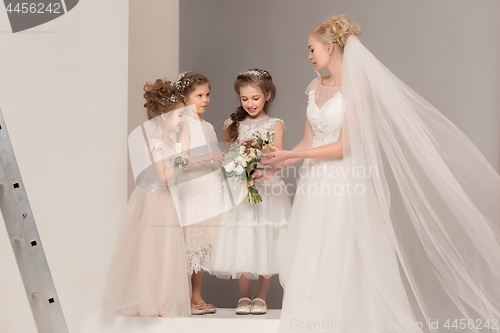 Image of Little pretty girls with flowers dressed in wedding dresses