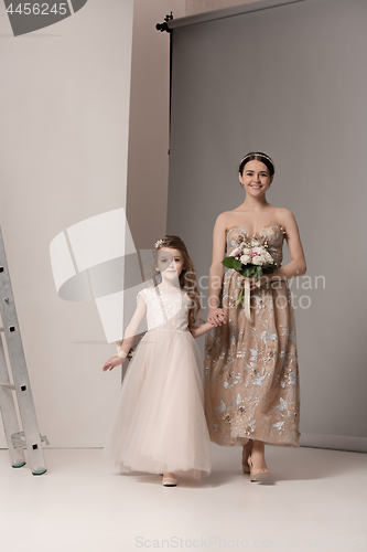 Image of Little pretty girls with flowers dressed in wedding dresses