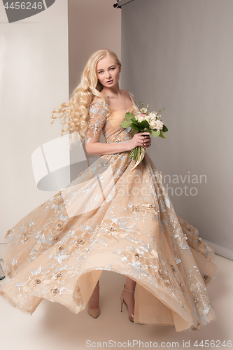 Image of Bride in beautiful dress standing indoors in white studio interior like at home. Trendy wedding style shot. Young attractive caucasian model like a bride tender looking.