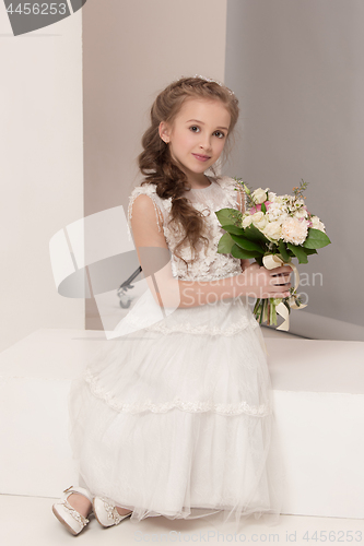 Image of Little pretty girl with flowers dressed in wedding dresses