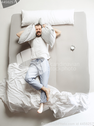 Image of Top view photo of young man sleeping in a big white bed