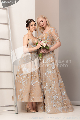 Image of Brides in beautiful dress standing indoors in white studio interior like at home. Trendy wedding style shot. Young attractive caucasian model like a bride tender looking.